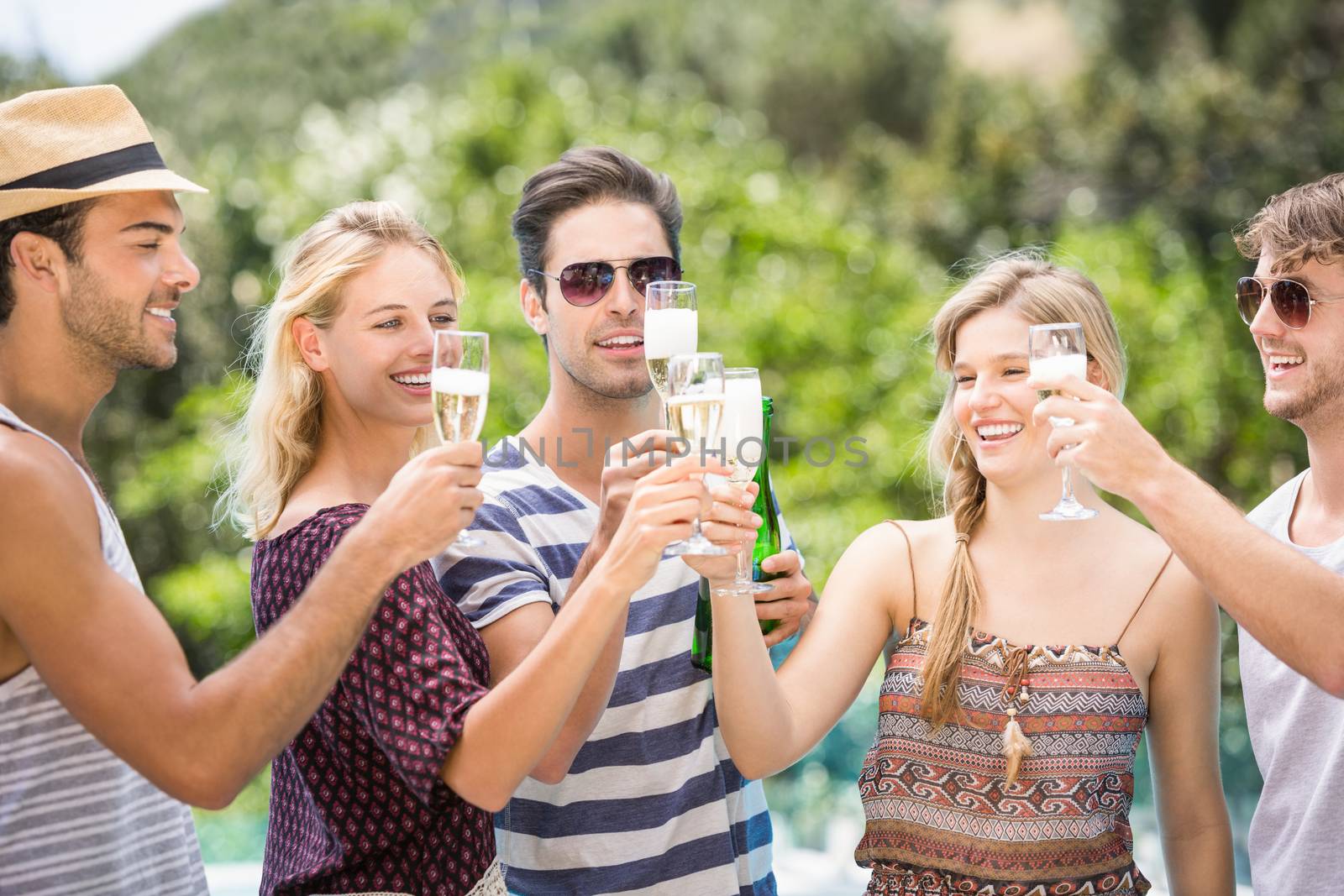 Group of happy friends toasting champagne flute outdoors