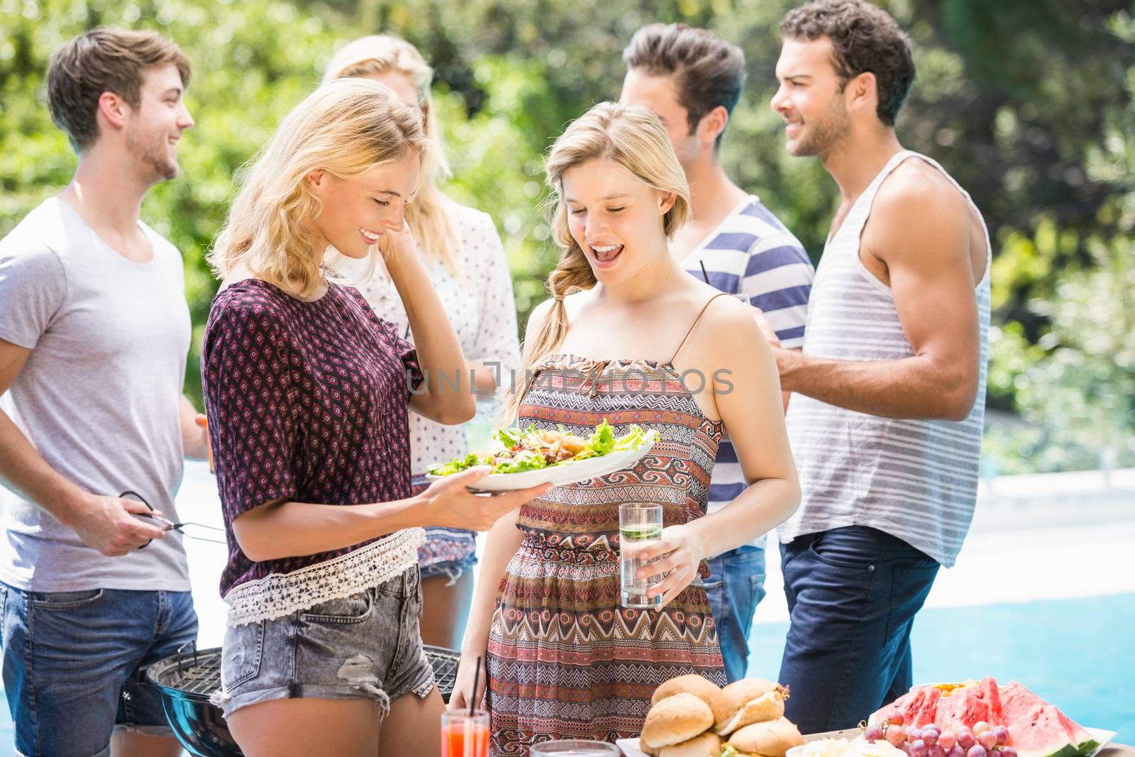 Friends preparing for outdoors barbecue party near pool