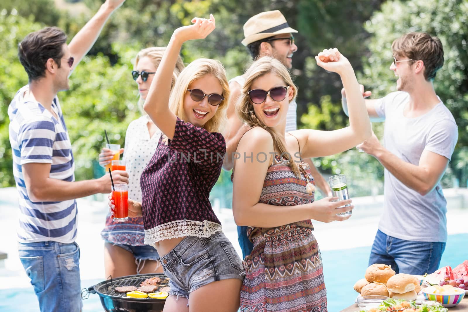 Group of friends dancing at outdoors barbecue party near pool