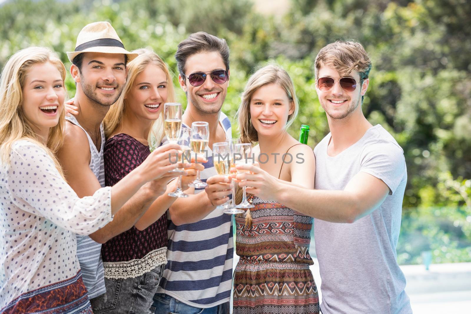 Group of happy friends toasting champagne glasses outdoors