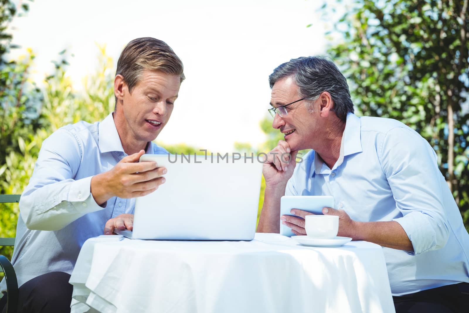 Two businessmen meeting in a restaurant using laptop in the garden