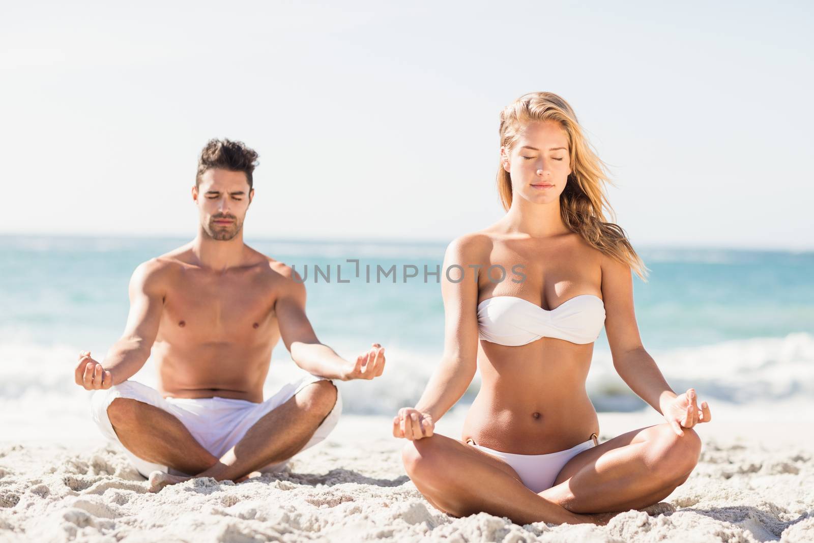 Happy couple doing yoga on the beach