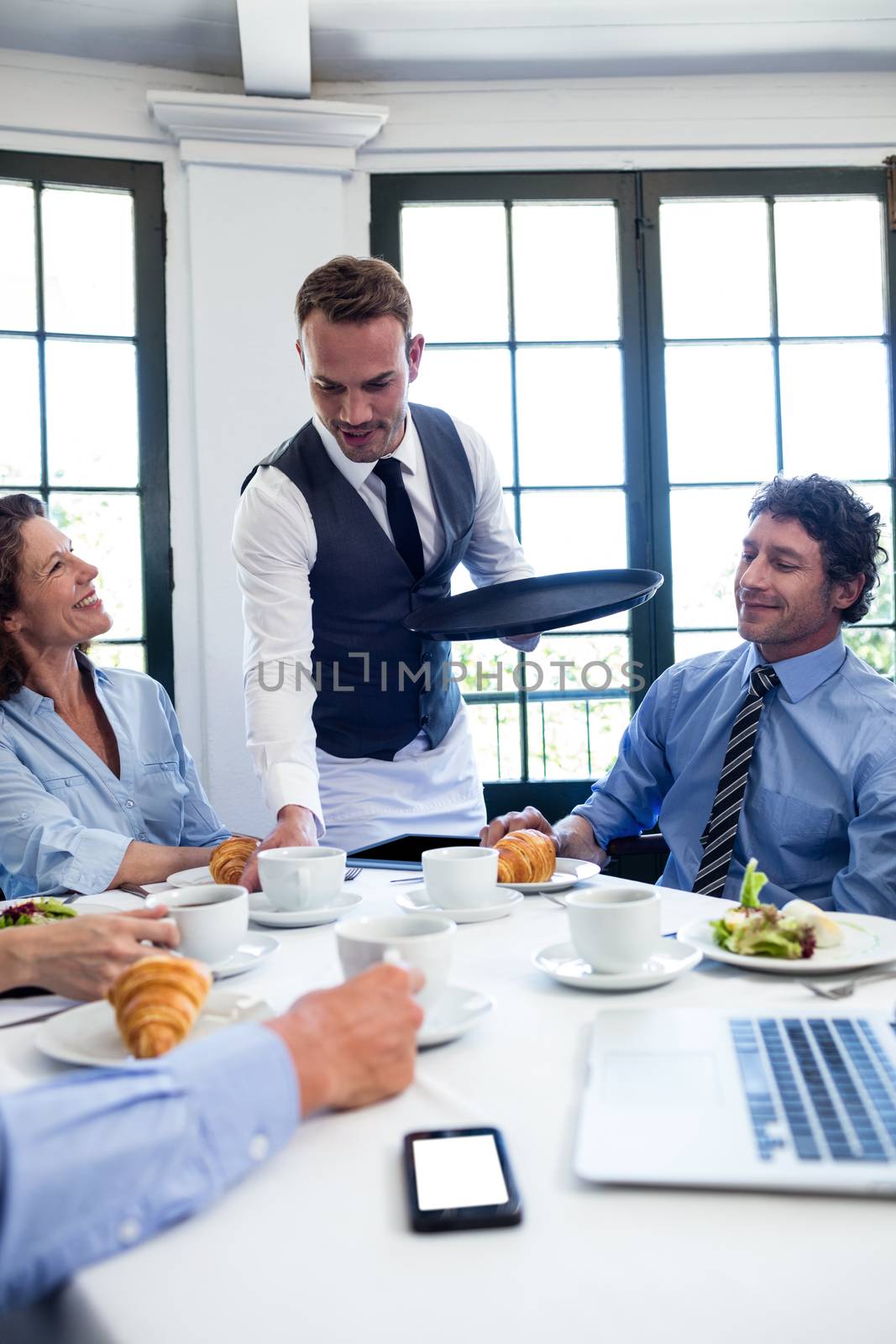 Waiter serving coffee to business people by Wavebreakmedia