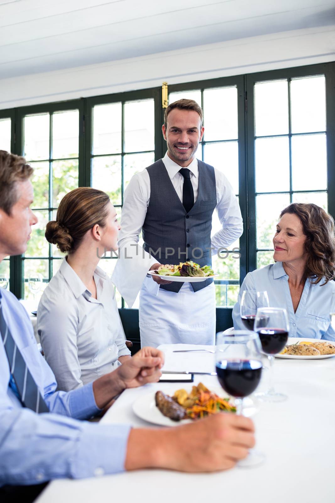 Waiter serving salad to business people by Wavebreakmedia