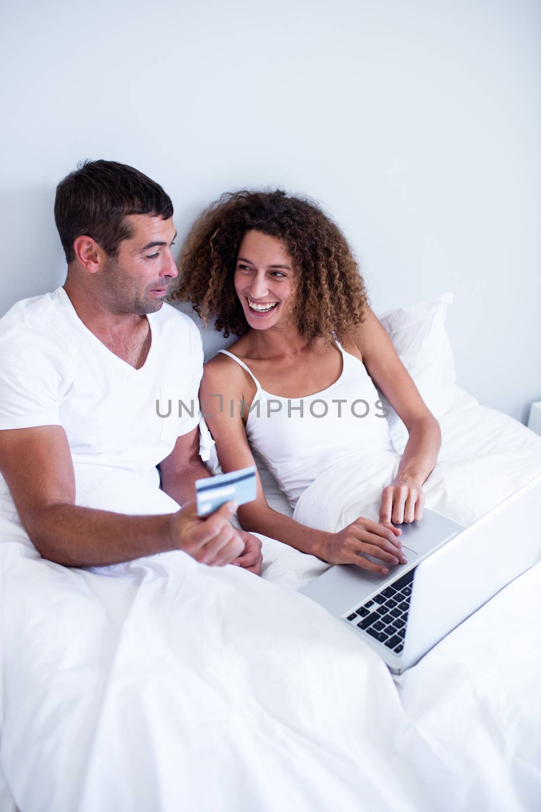 Couple shopping online in bedroom