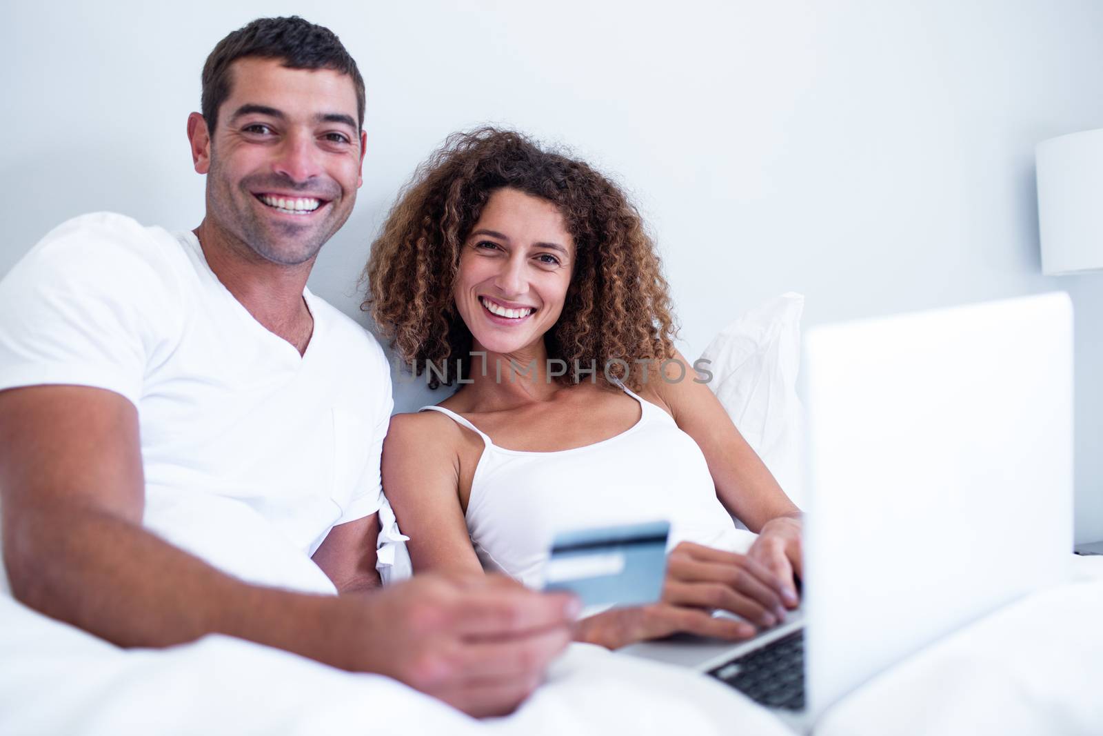 Portrait of couple shopping online in bedroom