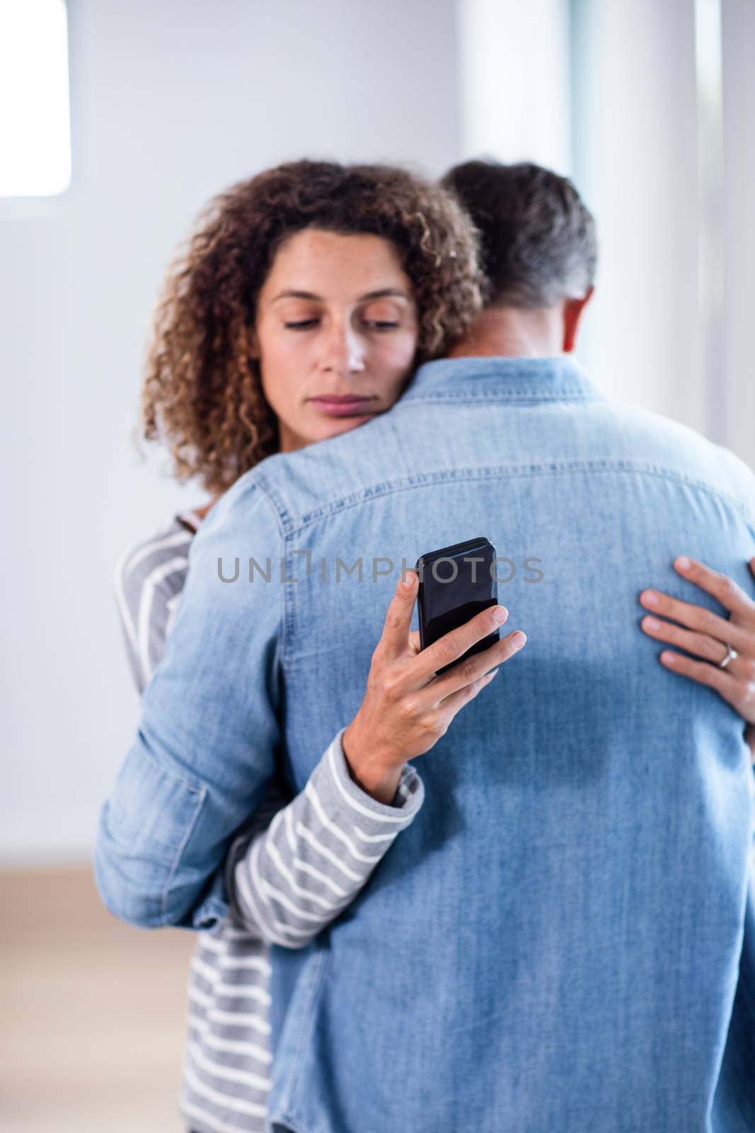Woman checking her mobile phone while embracing a man at home