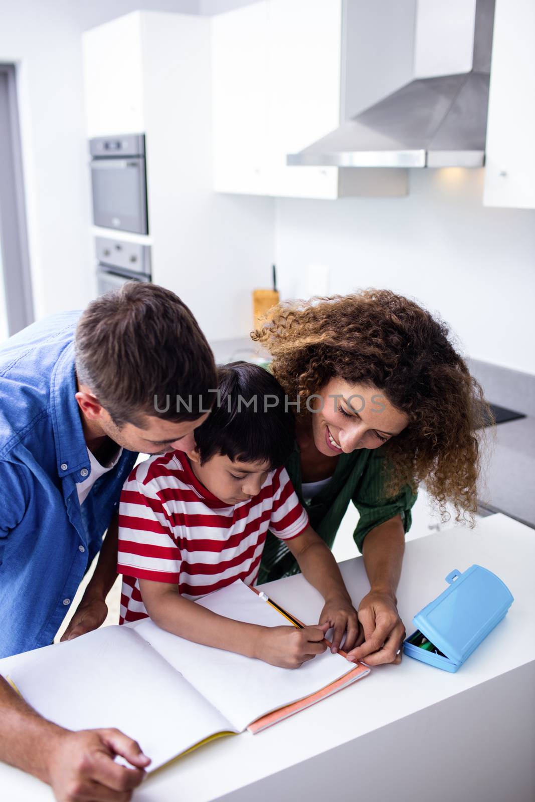 Parents helping son with homework in kitchen