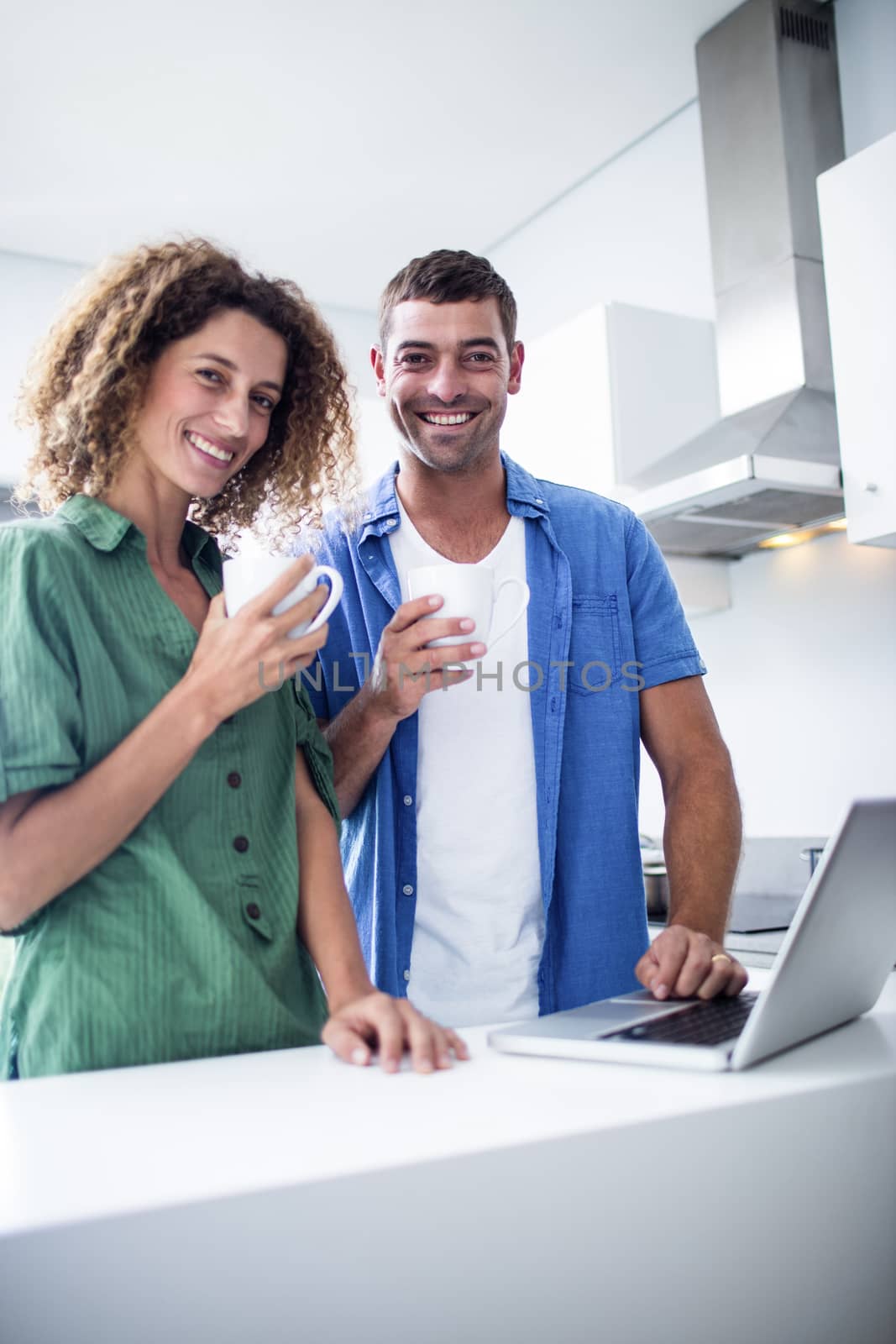 Portrait of couple using laptop while having a cup of coffee by Wavebreakmedia