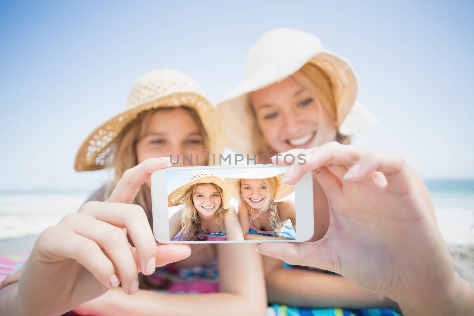 Two friends taking selfie while lying on the beach by Wavebreakmedia