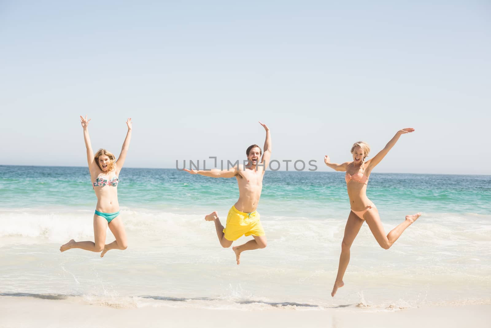 Happy young friends jumping on the beach by Wavebreakmedia