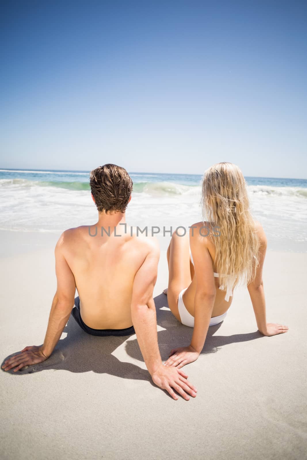Rear view of couple sitting on the beach by Wavebreakmedia