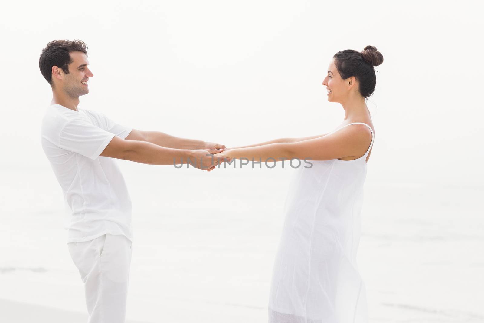 Romantic couple holding hands on the beach by Wavebreakmedia