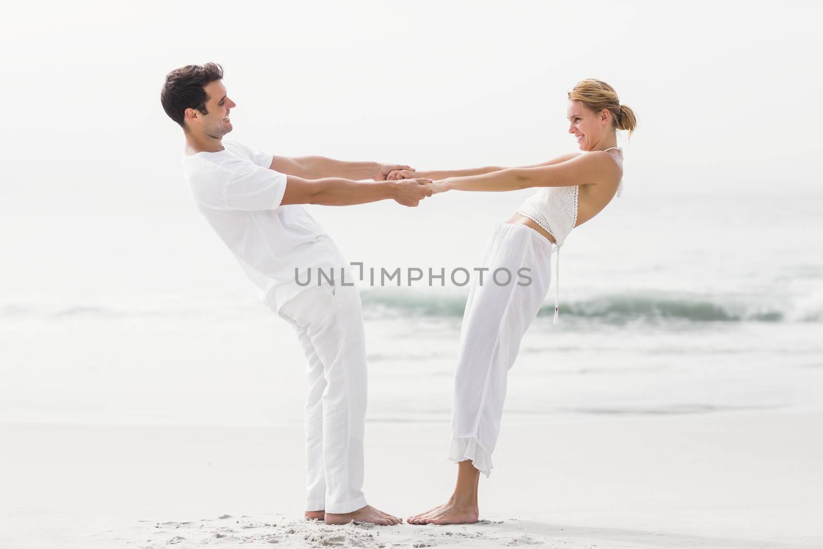 Romantic couple holding hands on the beach by Wavebreakmedia