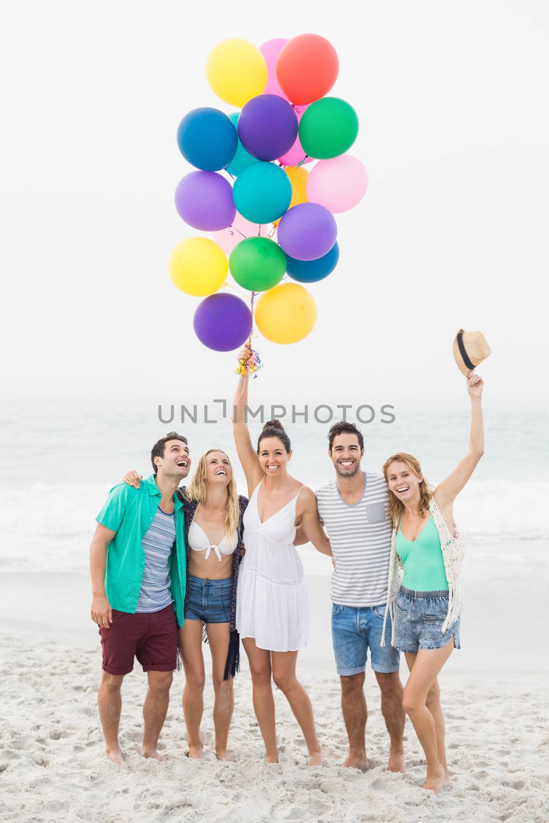 Group of friends standing on the beach with balloons by Wavebreakmedia