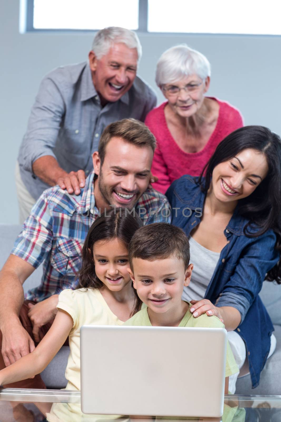 Happy family sitting on sofa using a laptop in living room