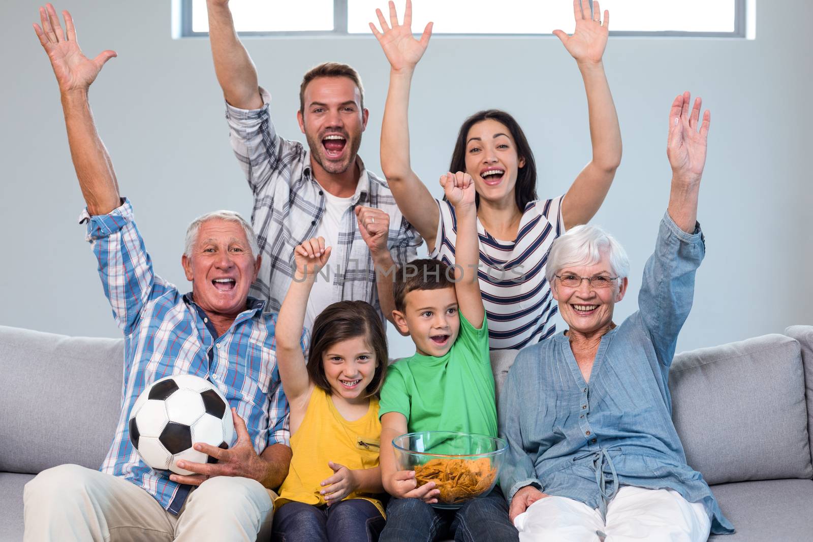 Happy family watching a football match at home by Wavebreakmedia