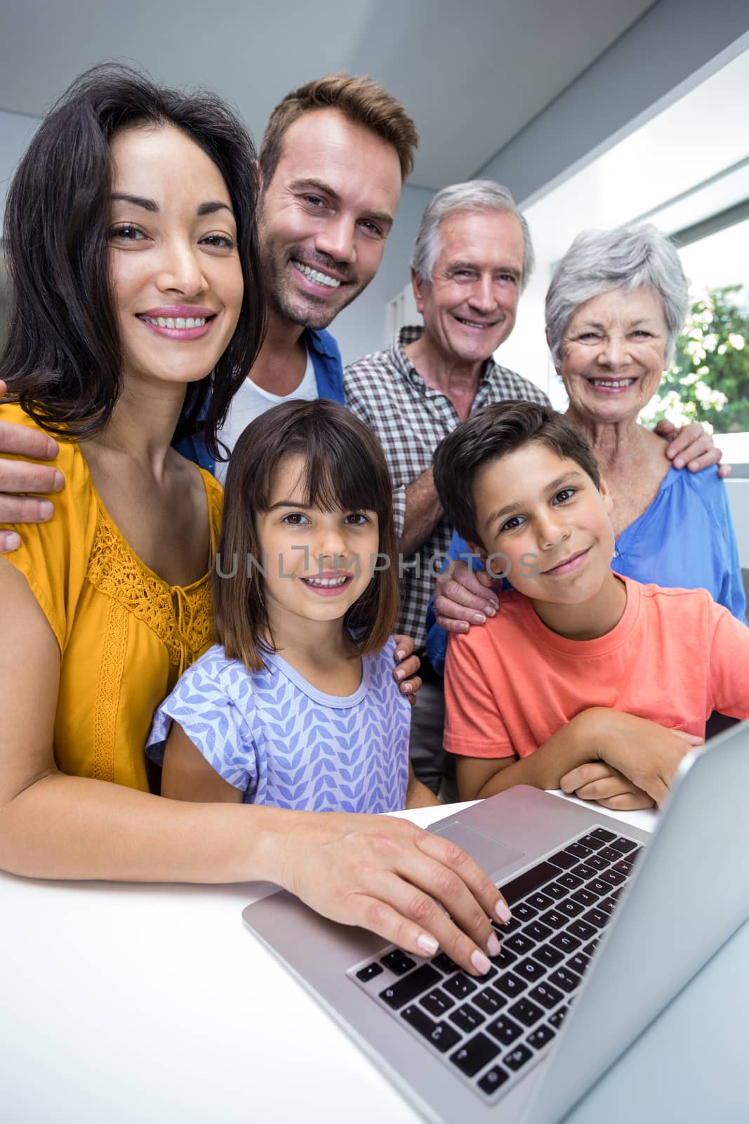 Portrait of happy family interacting using laptop in their living room