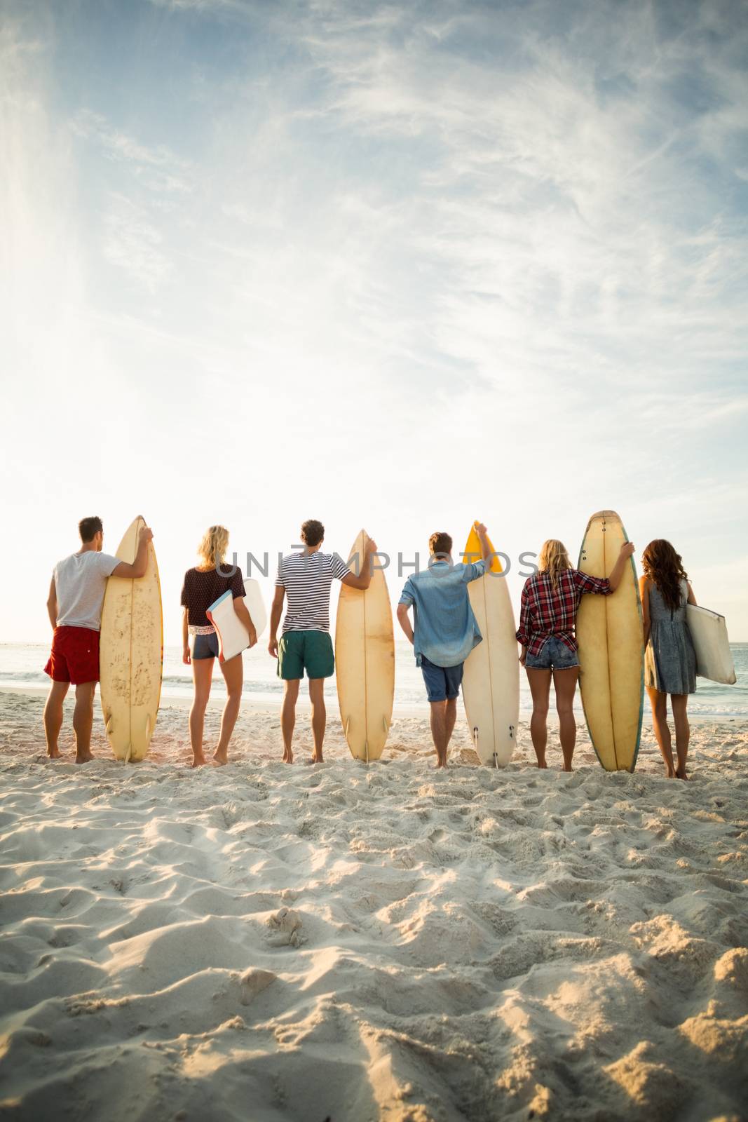 Friends holding surfboard on the beach on a sunny day