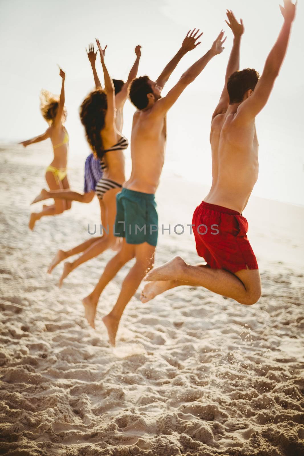 Friends jumping on the beach on a sunny day