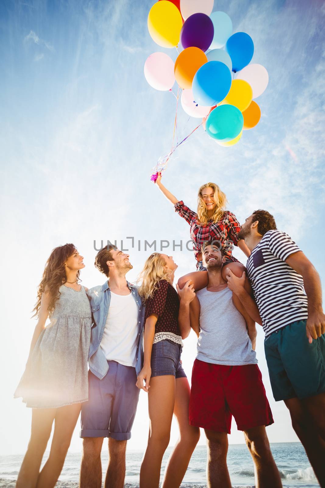 Friends posing with balloon on sand by Wavebreakmedia