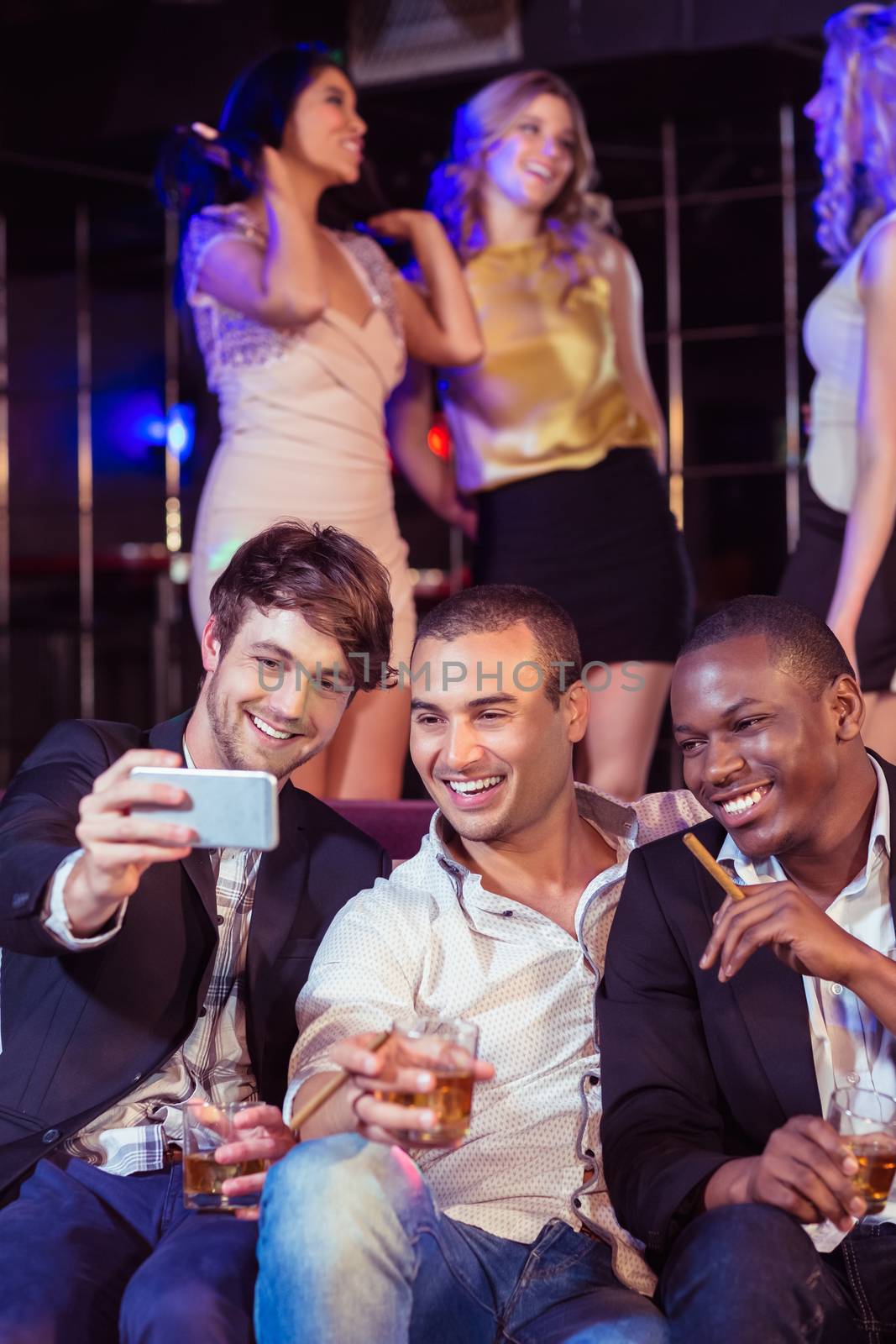 Happy friends taking selfie in a bar