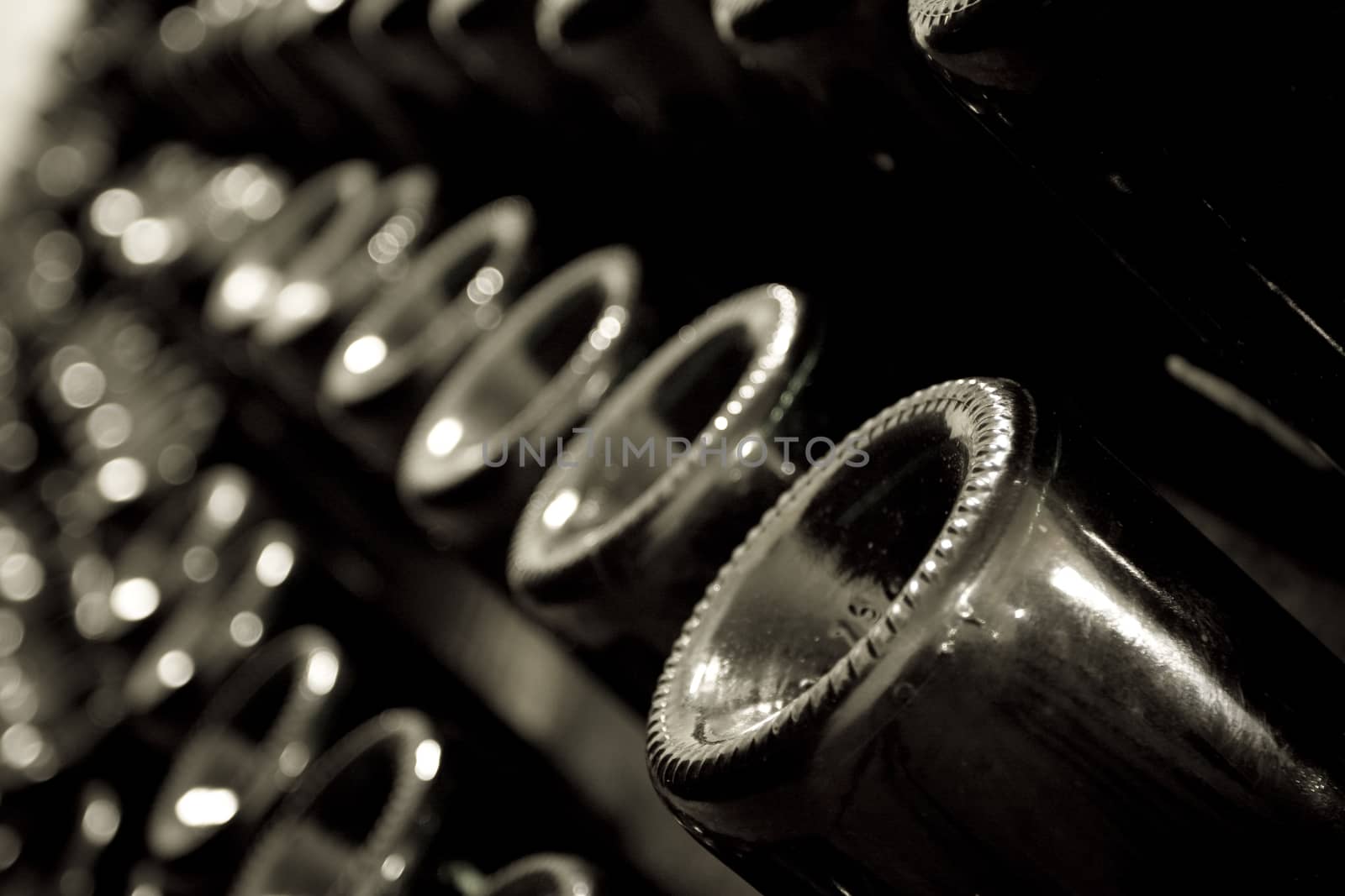 Horizontal perspective view of rows of many champagne bottles in a wine cellar