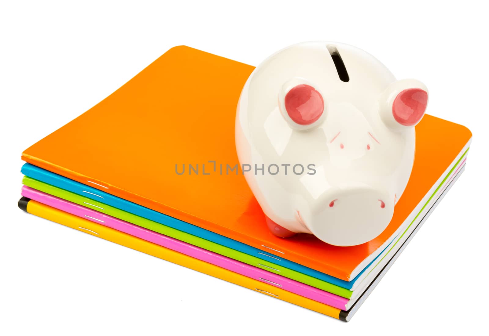Piggy bank on pile of copybooks on isolated white background
