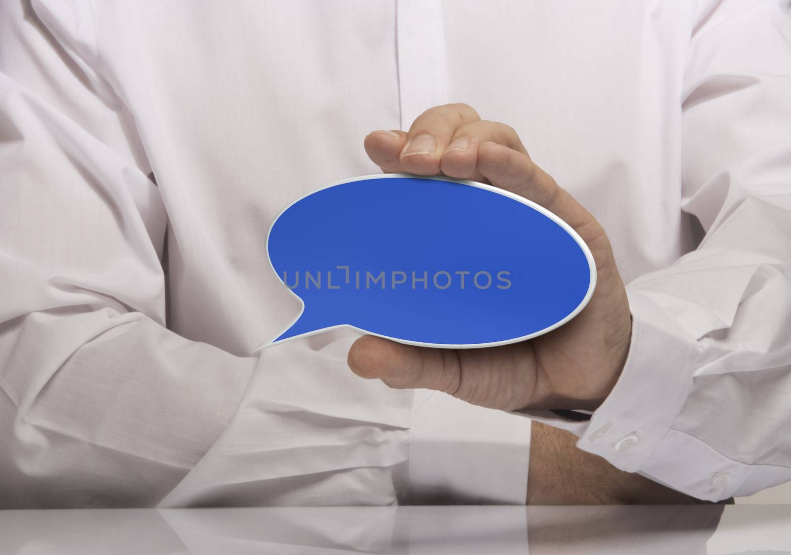 Image of a man hand holding empty blue speech balloon, white shirt and reflexion. 