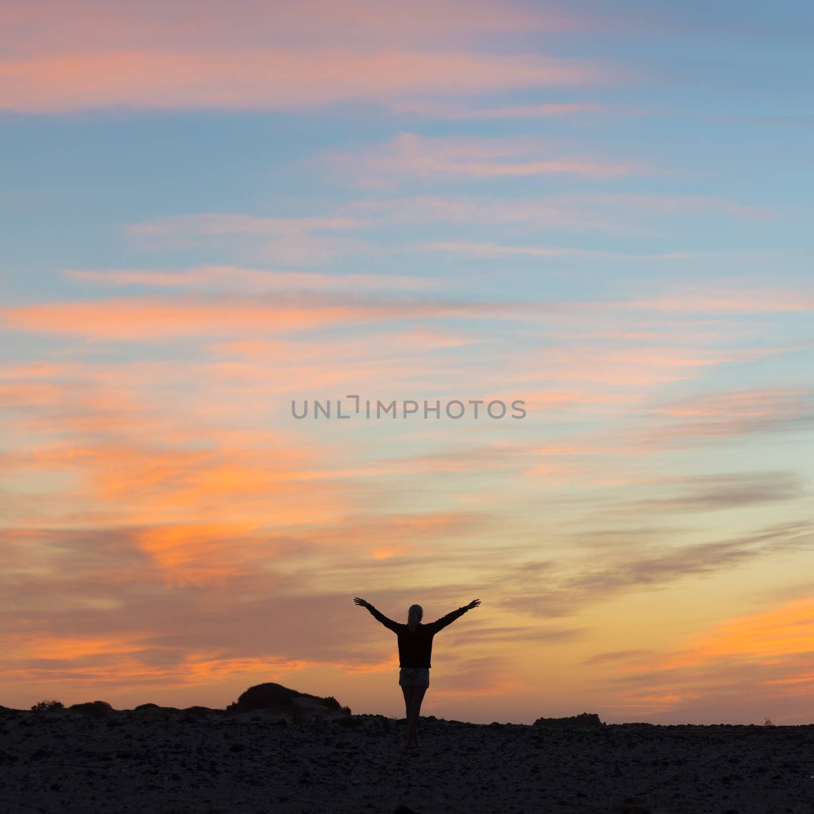 Silhouette of free woman enjoying freedom feeling happy at sunset. Serene relaxing woman in pure happiness and elated enjoyment with arms raised outstretched up. 