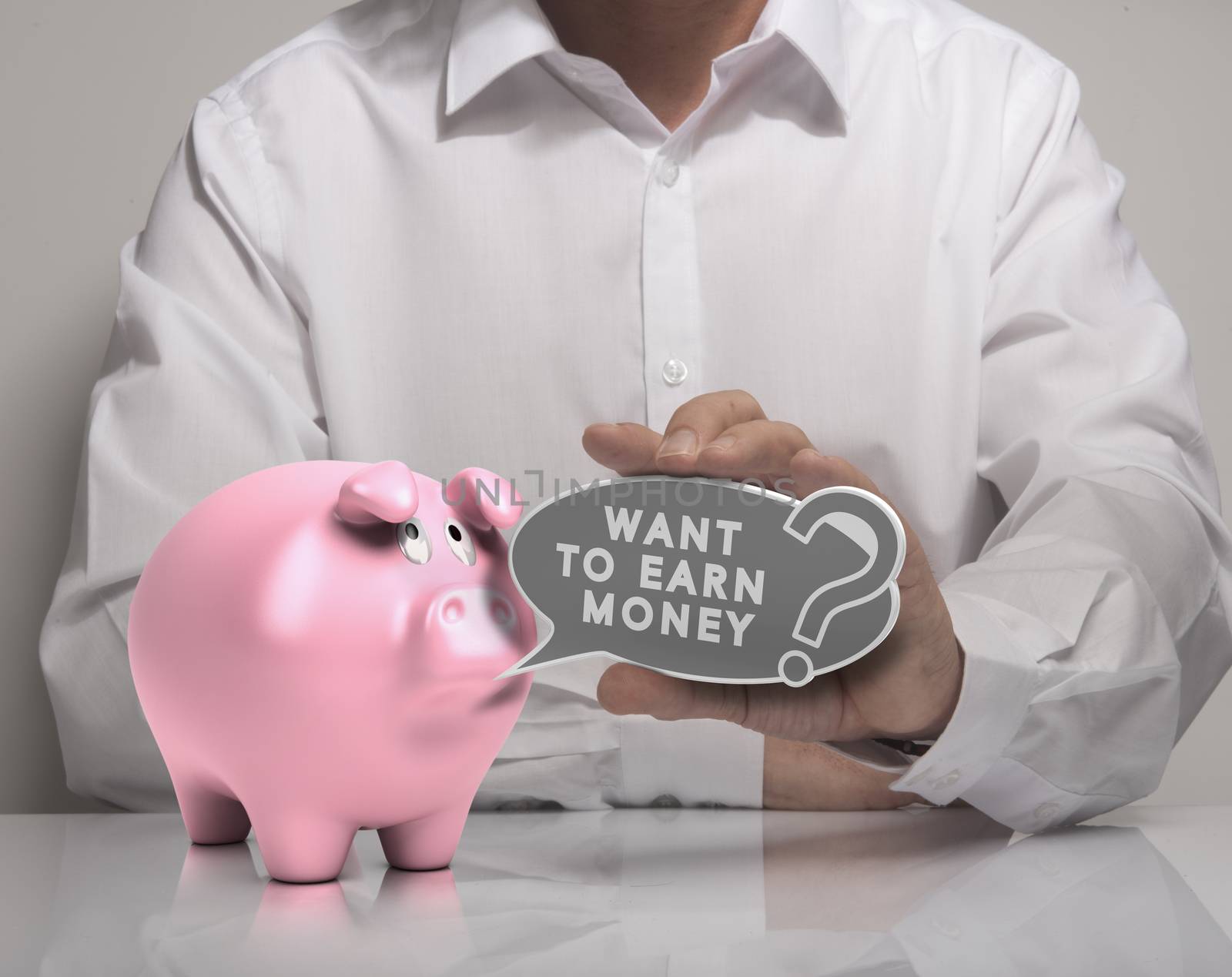 Image of a man hand holding speech balloon with the text want to earn money and pink piggy bank, white shirt. Concept for money earning.