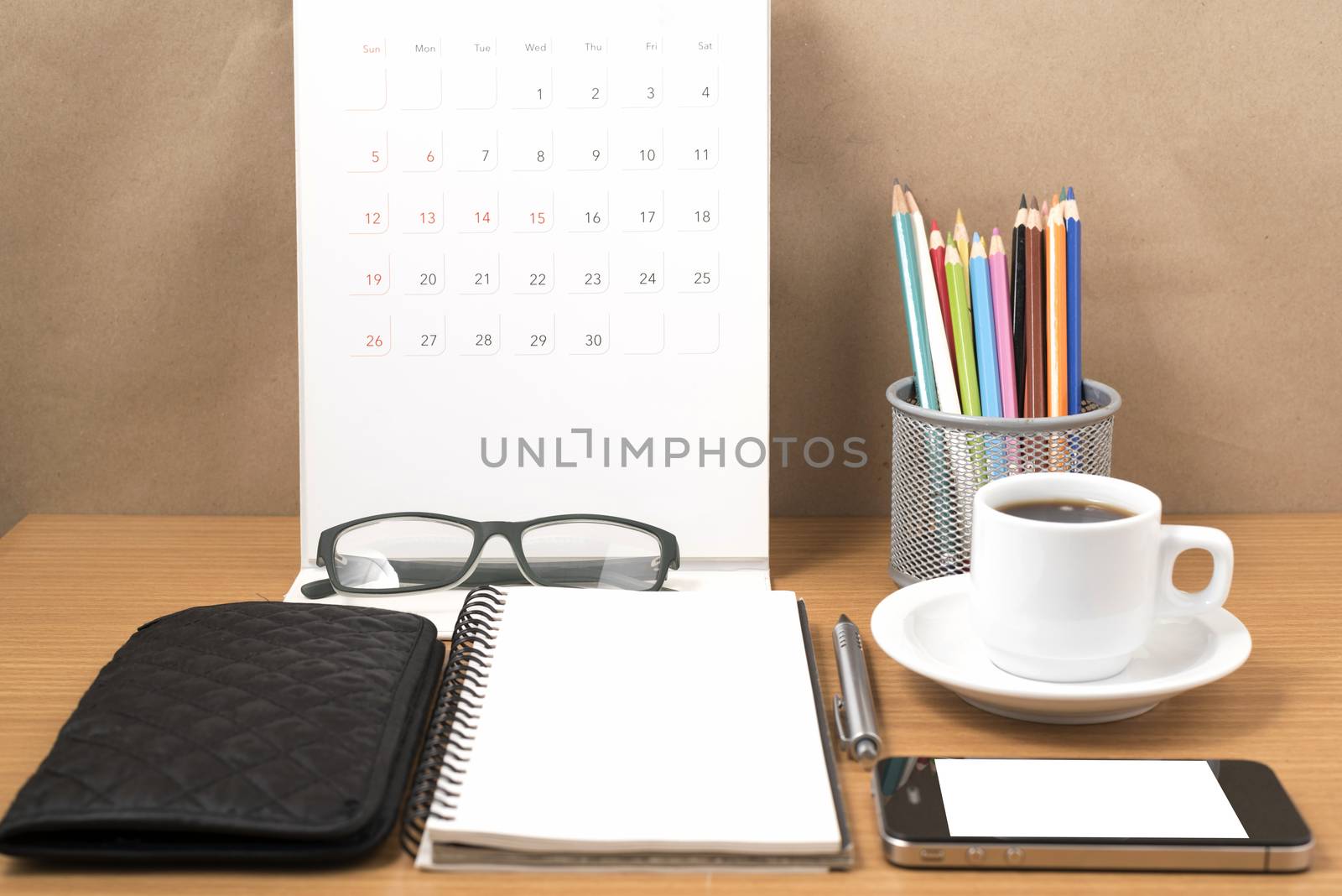 office desk : coffee with phone,wallet,calendar,heart,notepad,eyeglasses,color pencil box on wood background