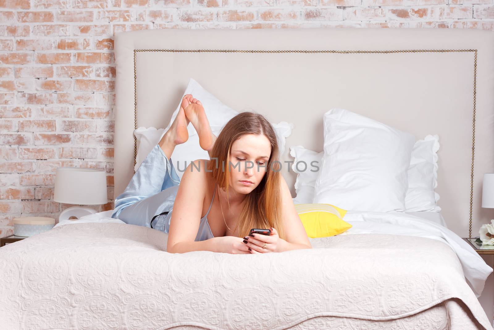 Young woman using smartphone on the bed by victosha