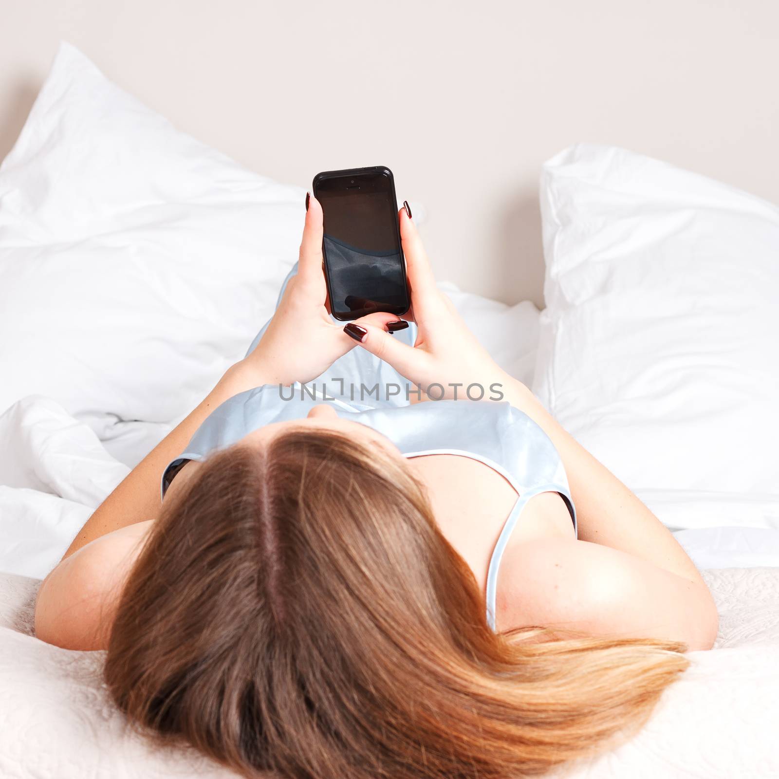 Young woman using smart phone on the bed