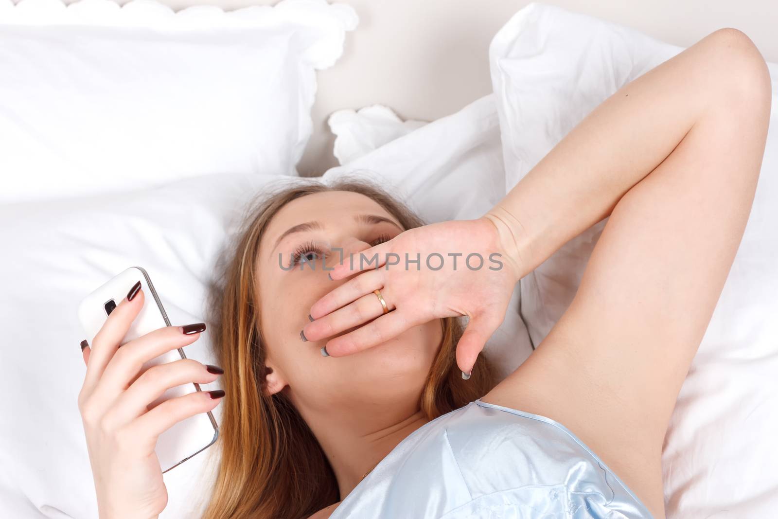 Young woman using smartphone on the bed by victosha