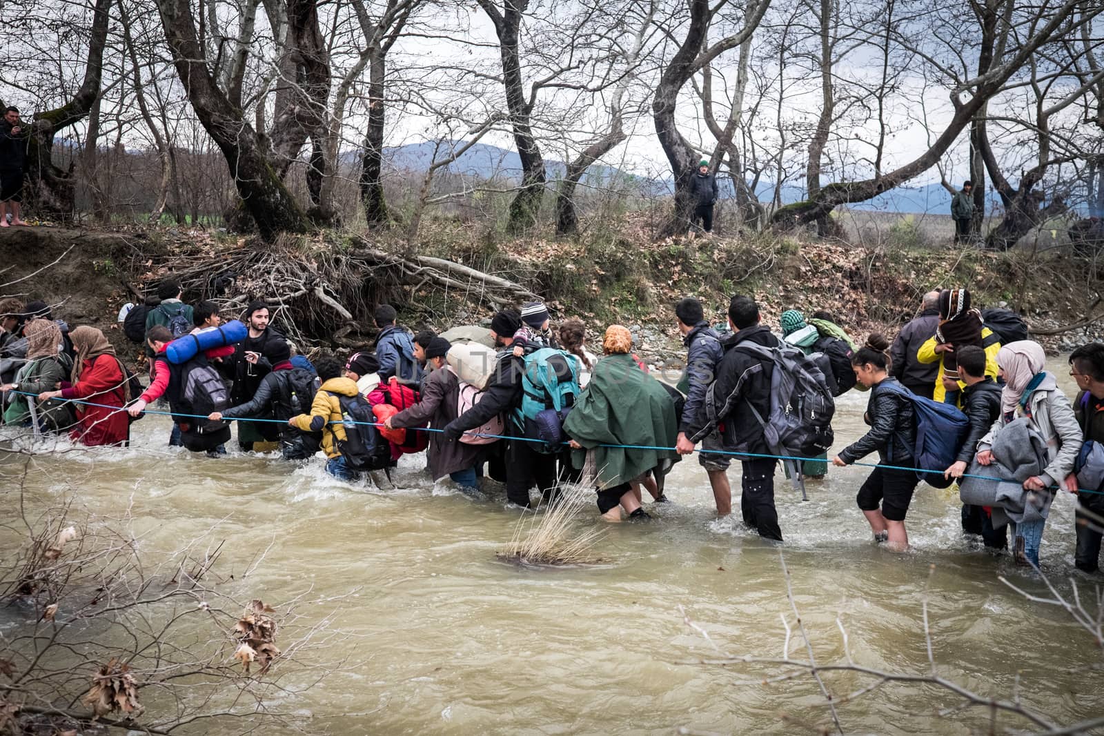 GREECE, Idomeni: Migrants and refugee cross a surging river on their way to Macedonia from a makeshift camp at the Greek-Macedonian border, near the Greek village of Idomeni on March 14, 2016, where thousands of them are stranded by the Balkan border blockade. More than 14,000 people are stuck on the Greek side of the border in an overcrowded camp at Idomeni after the main migrant route to western Europe through the Balkans was effectively shut down last week.