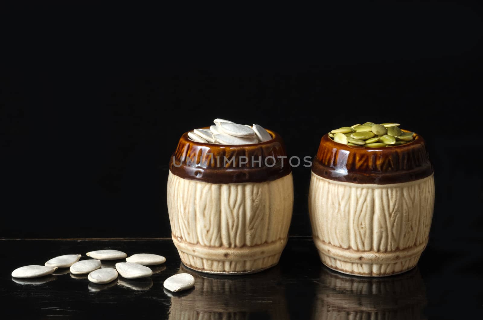 Pumpkin seeds in a ceramic bowl on a black background and a vintage black lacquered surface