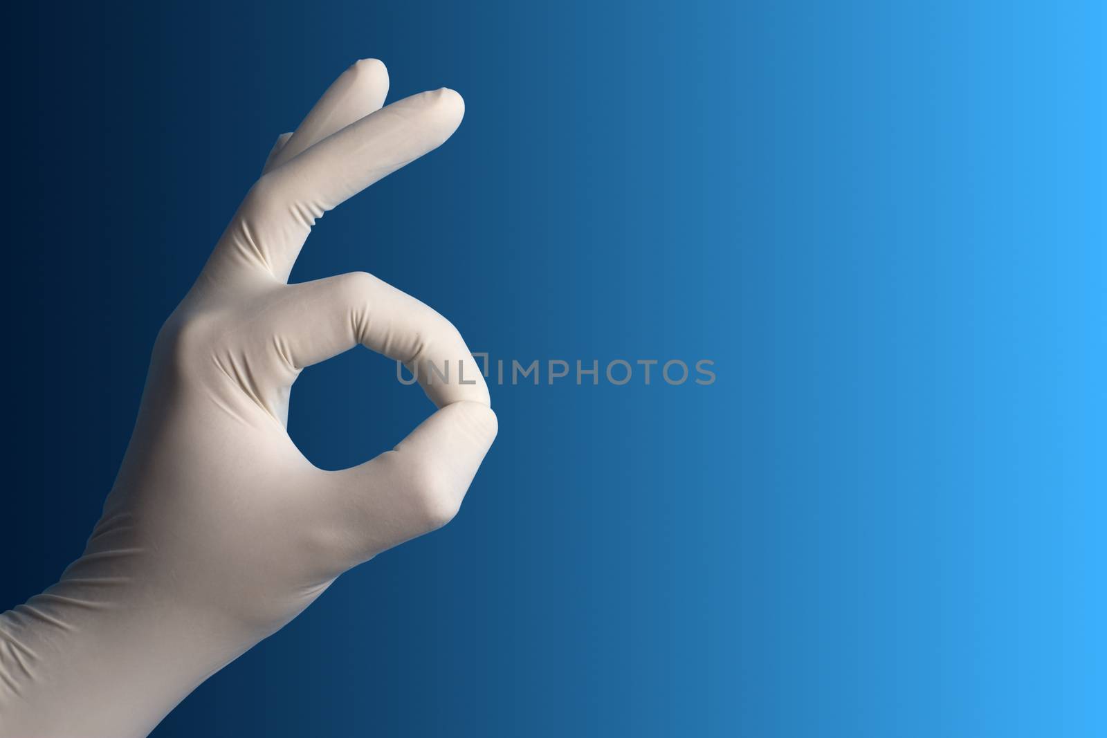 Hand with a white surgical glove showing the ok sign against a blue background