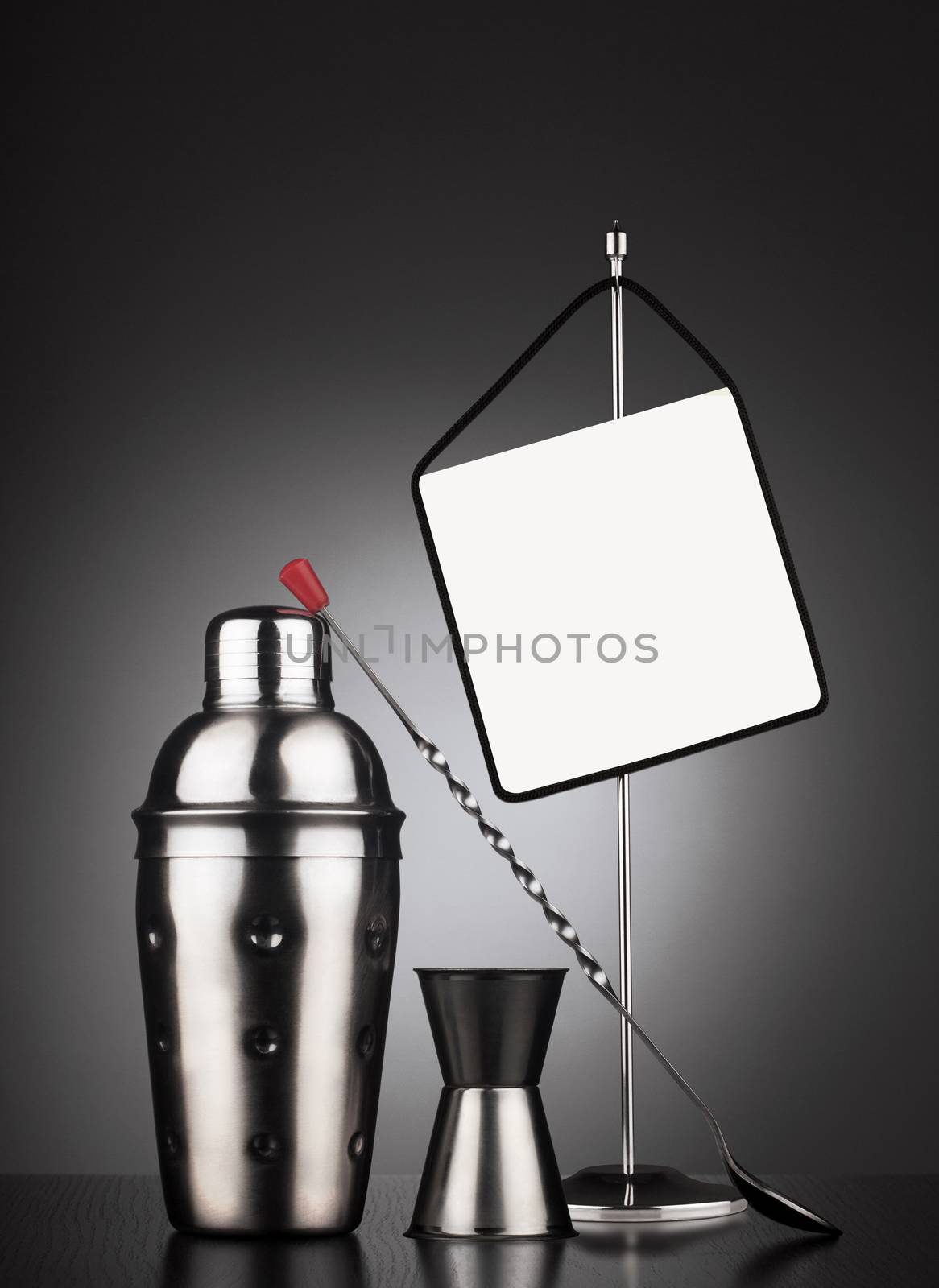 Cocktail set of tools including shaker and spoon next to a table stander with display area for offers or headline