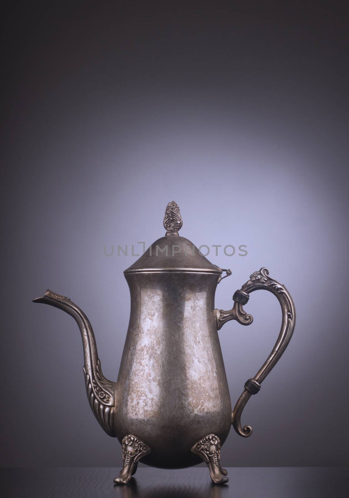 Silver vintage tea kettle with engravings on gray background