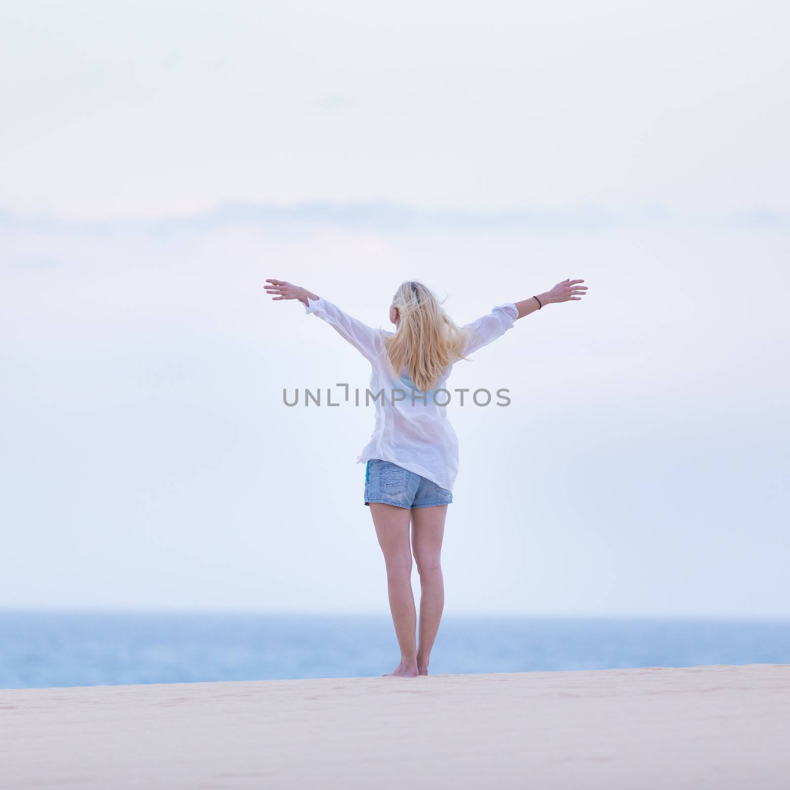 Relaxed woman enjoying freedom feeling happy at beach in the morning. Serene relaxing woman in pure happiness and elated enjoyment with arms raised outstretched up. 