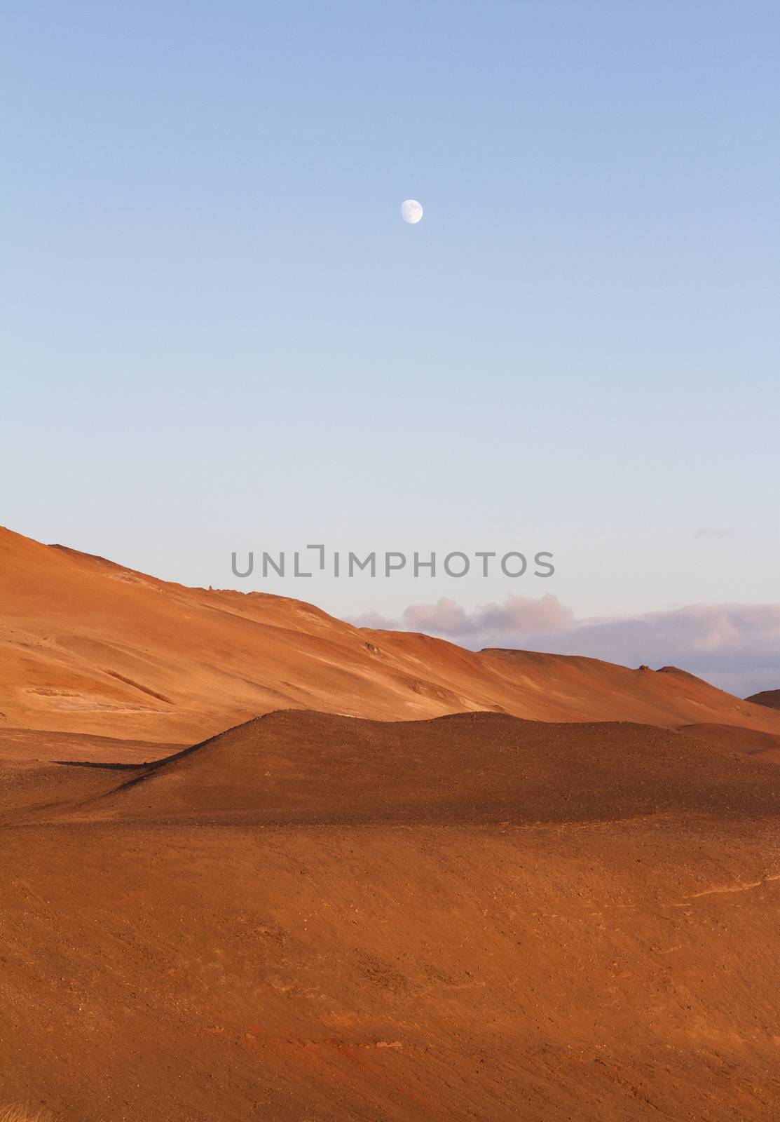 Vertical view of ash volcanic mountains with blue sky and moon above near Myvatn baths in Iceland