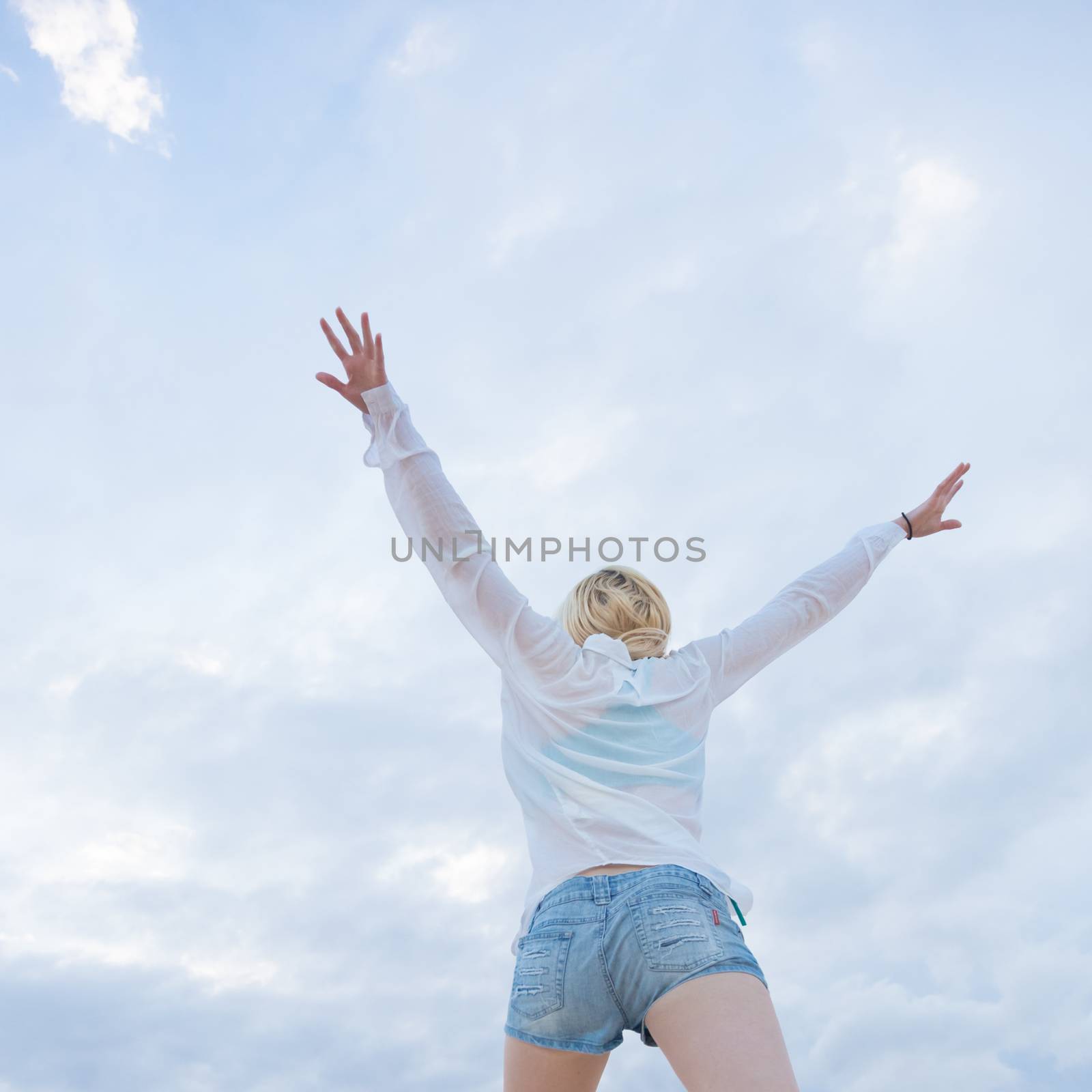 Relaxed woman enjoying freedom, feeling happy. Serene relaxing woman in pure happiness and elated enjoyment, jumping with arms outstretched up