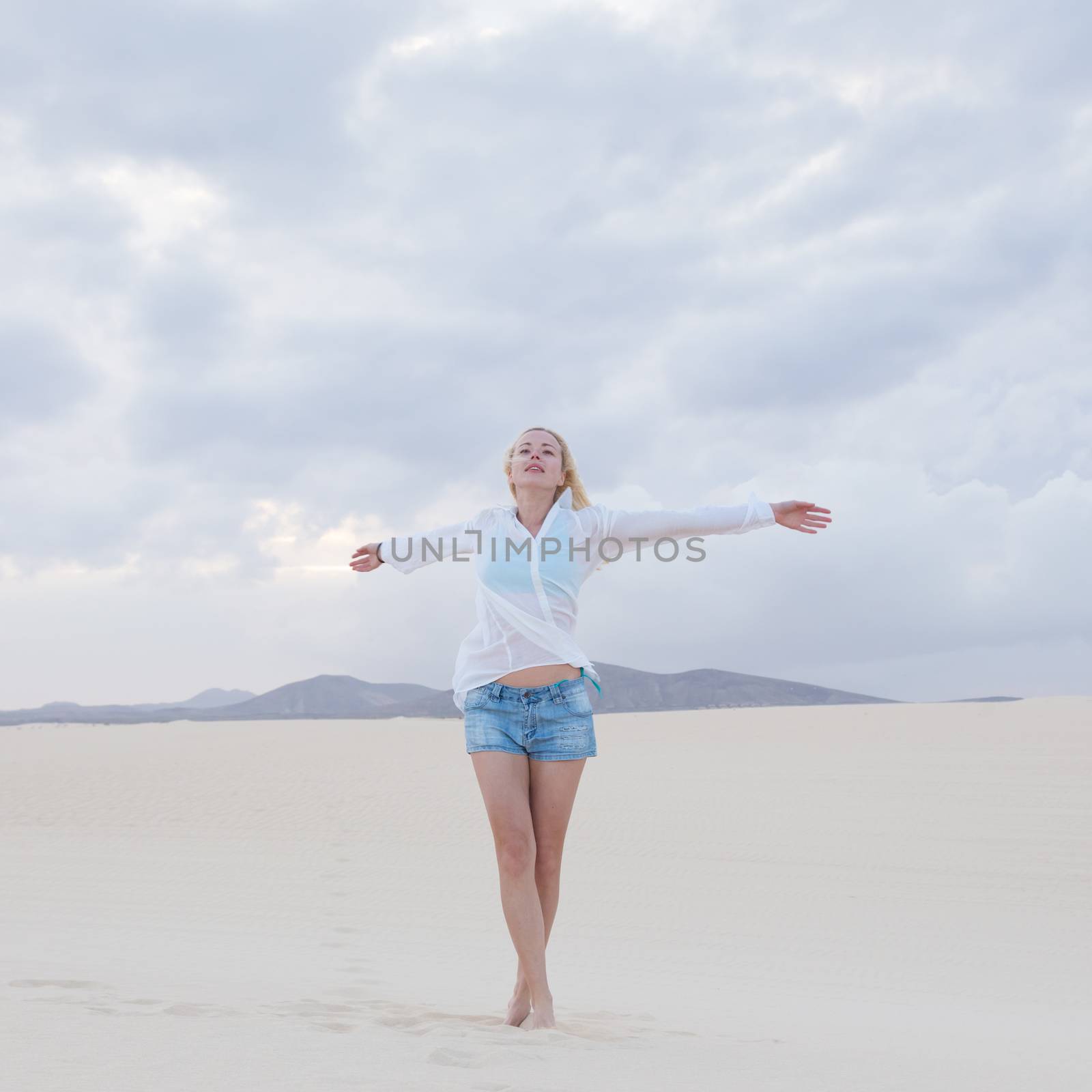 Carefree woman enjoying freedom on beach. by kasto