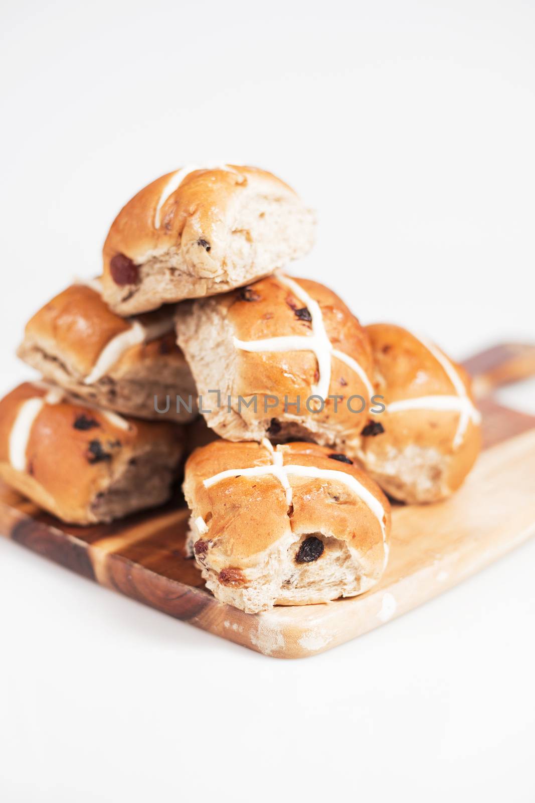 Hot cross buns on a timber board with a white background.