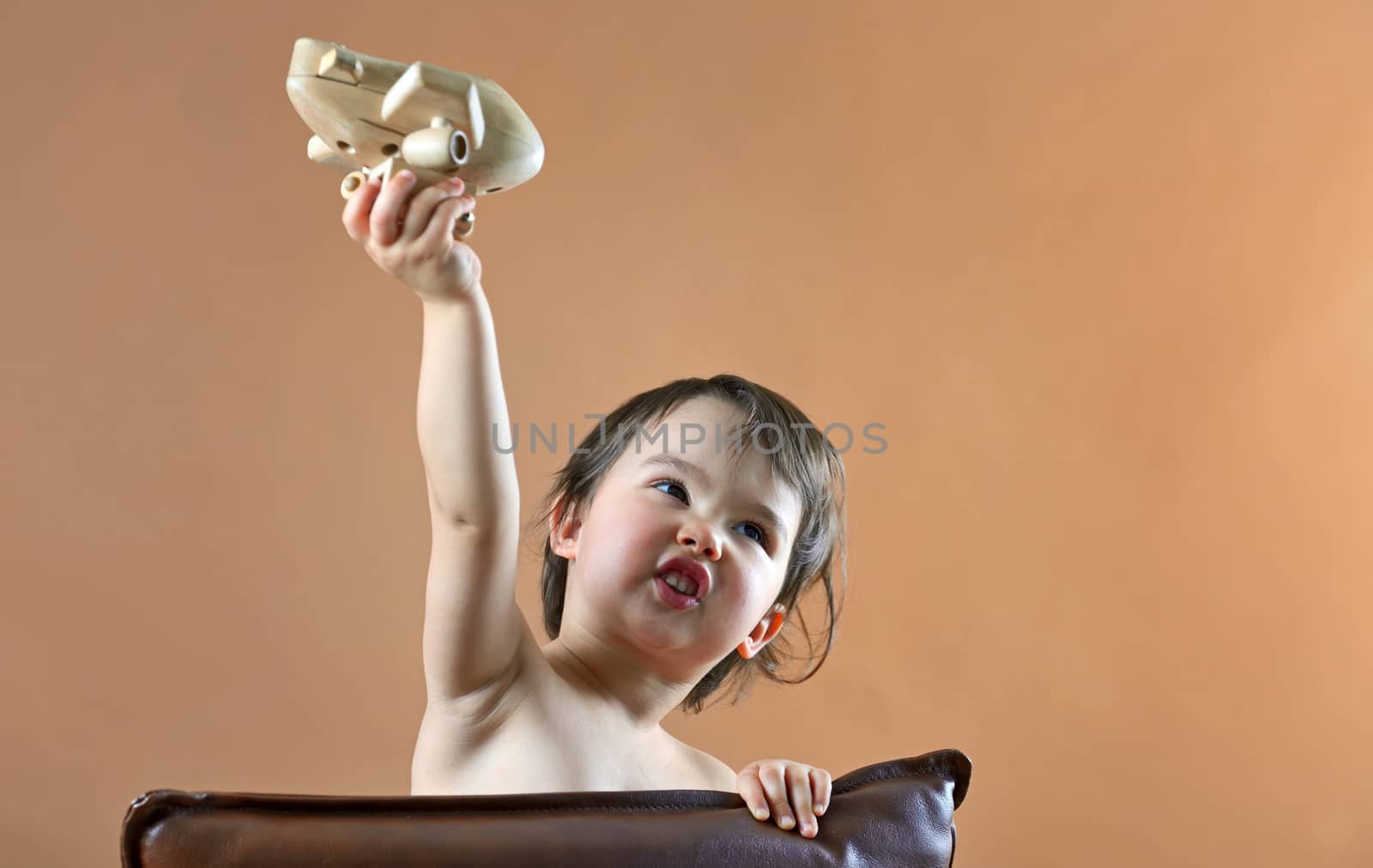 happy child girl playing with toy airplane in studio