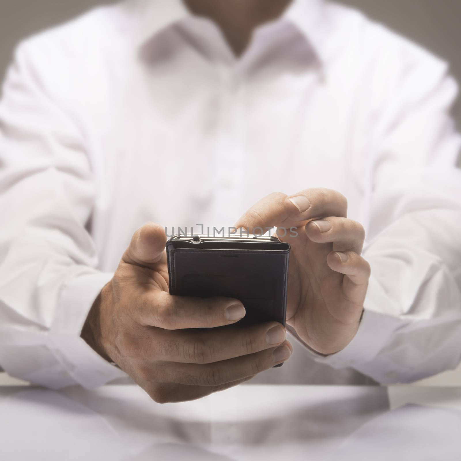 One smartphone in hands of a businessman wearing a white shirt 
