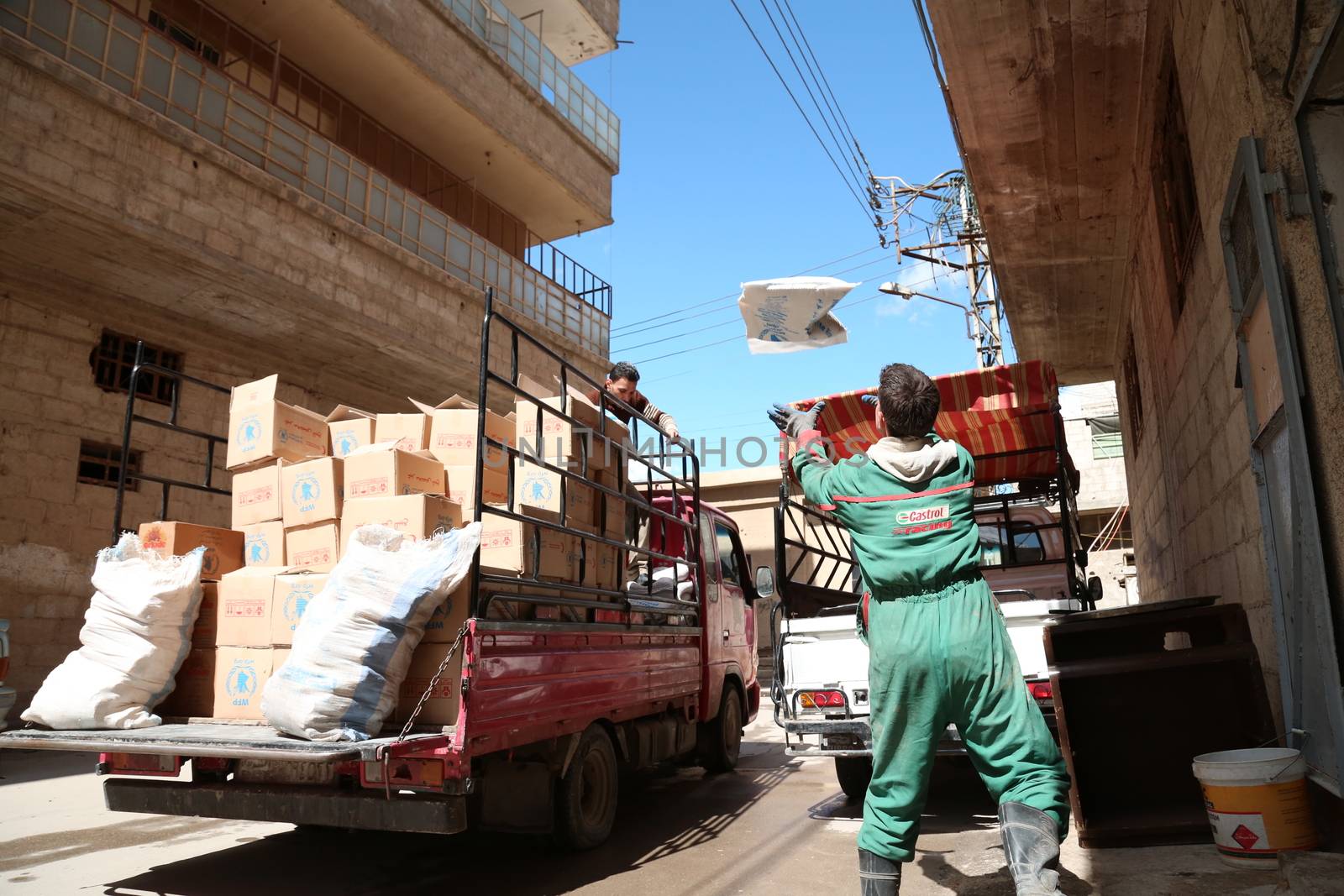 SYRIA, Saqba: A man carries a sack of wheat as Syrian Red Crescent staff survey the delivery of humanitarian aid at a warehouse in Saqba, in the rebel-held Eastern Ghouta area, southern Syria, on the outskirts of the capital Damascus on March 15, 2016 during an operation in cooperation with the UN to deliver aid to thousands of besieged Syrians. UN aid convoys head to two Syrian towns besieged by government forces to deliver life-saving food and medicine to some 30,000 people, a UN spokesman said. 