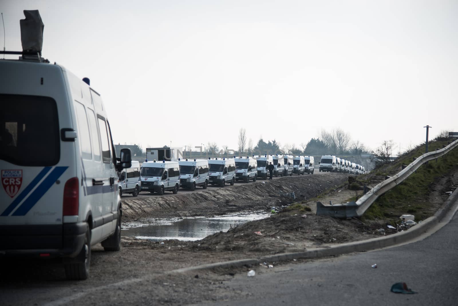 FRANCE, Calais: French anti-riot policemen stand guard during the dismantling of the southern part of the so-called 'Jungle' migrant camp in Calais, northern France, on March 14, 2016.Thousands of migrants have been living in the Jungle and other smaller camps along the northern coast, desperate to reach Britain where many have family or community ties and see better hopes of gaining employment or education. 