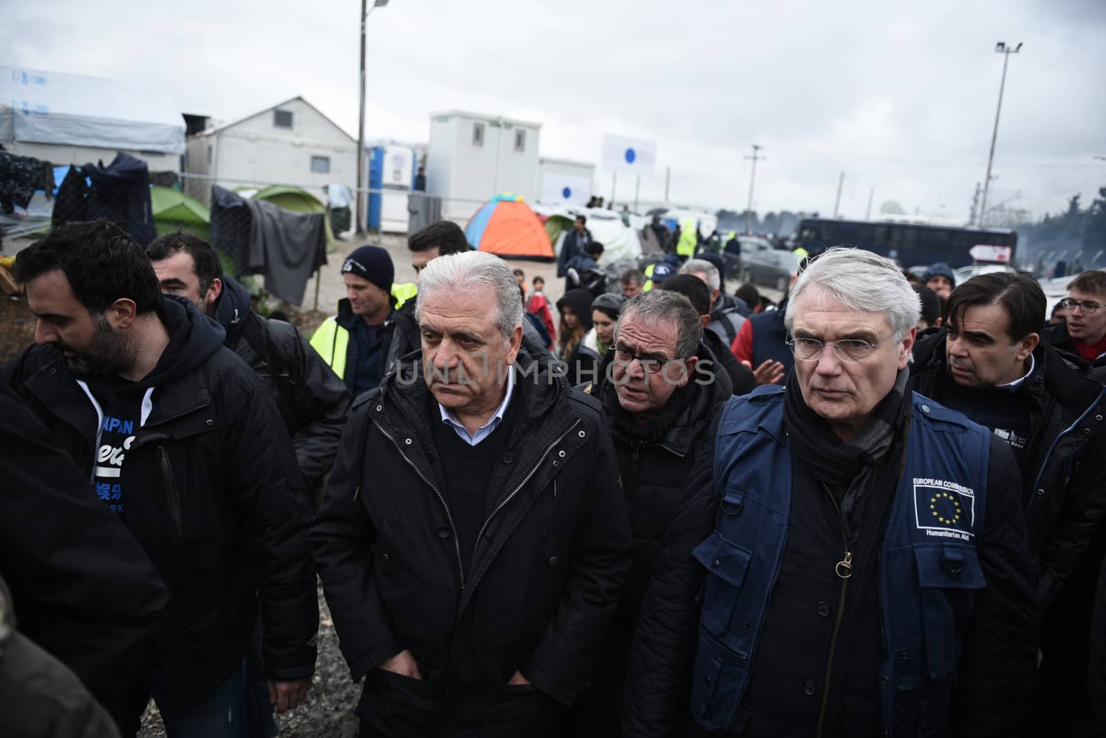 GREECE, Idomeni: Dimitris Avramopoulos, European commissioner for migration (C) walks along the railway tracks next to tents at the Idomeni refugee camp on the Greek Macedonia border on March 15, 2016 in Idomeni, Greece. Yesterday, an attempt by some of the residents of the camp to cross the border to Macedonia was thwarted by Macedonian security forces who returned the migrants to Greece. The decision by Macedonia to close its border to migrants last week has left thousands of people stranded at the Greek transit camp. The closure, following the lead taken by neighbouring countries, has effectively sealed the so-called western Balkan route, the main migration route which has been used by hundreds of thousands of migrants to reach countries in western Europe, such as Germany. Humanitarian workers have described the conditions at the camp as desperate, which has been made much worse by recent spells of heavy rain.